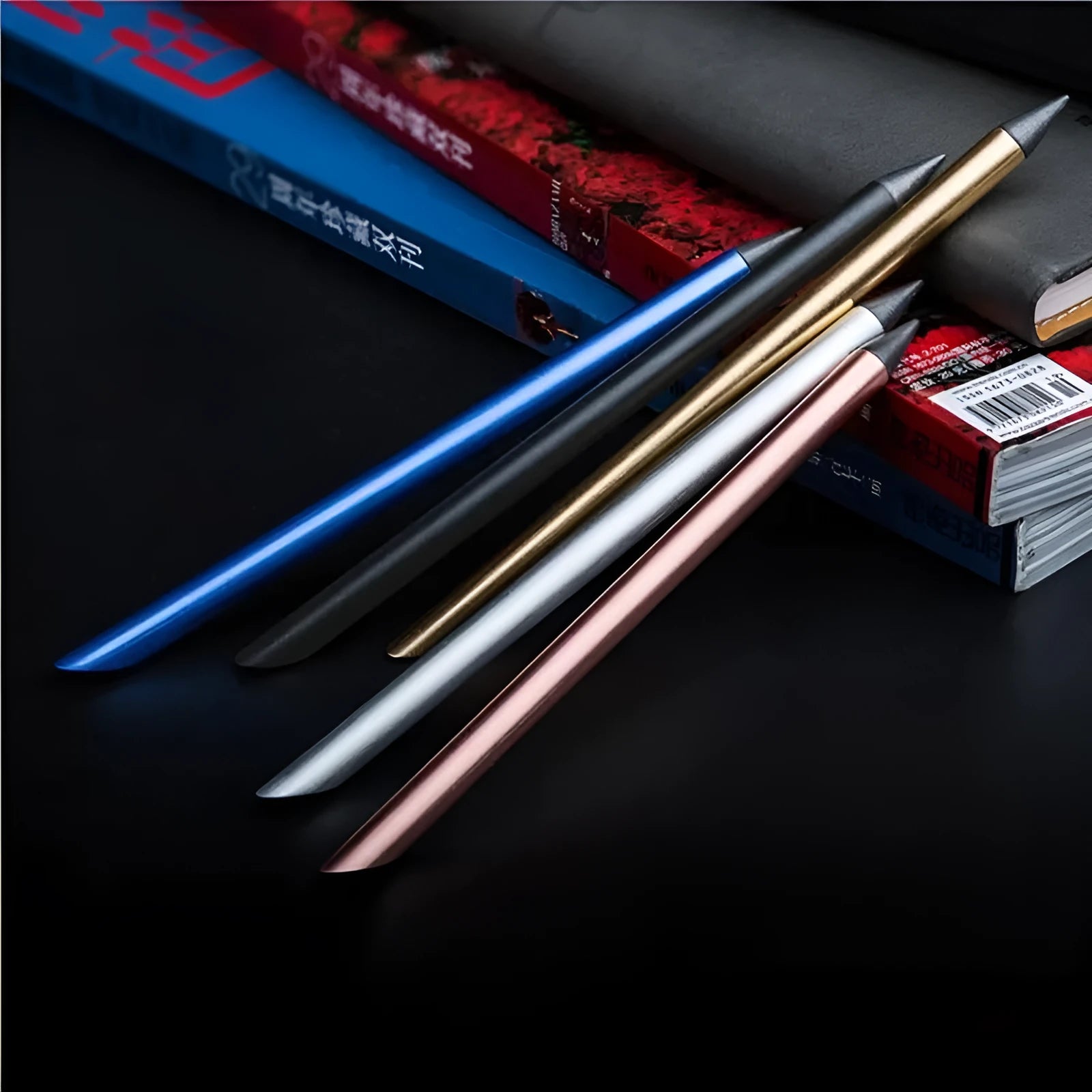Silver inkless metal pen with a 0.5 mm alloy tip, shown with its spare nib and carry bag on a desk.