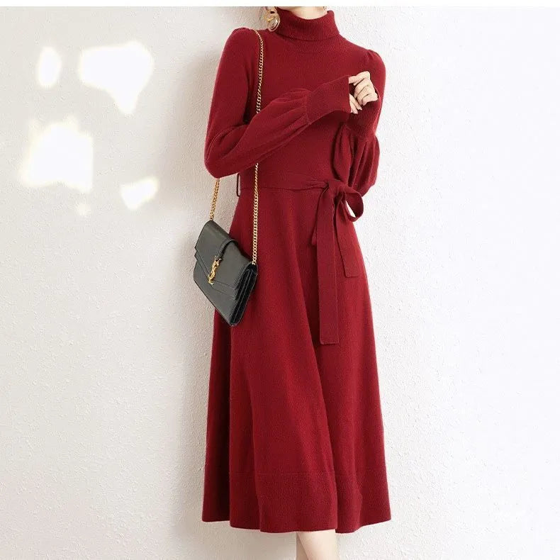 A woman wearing a rose red knitted turtleneck dress with a loose midi skirt and long sleeves.