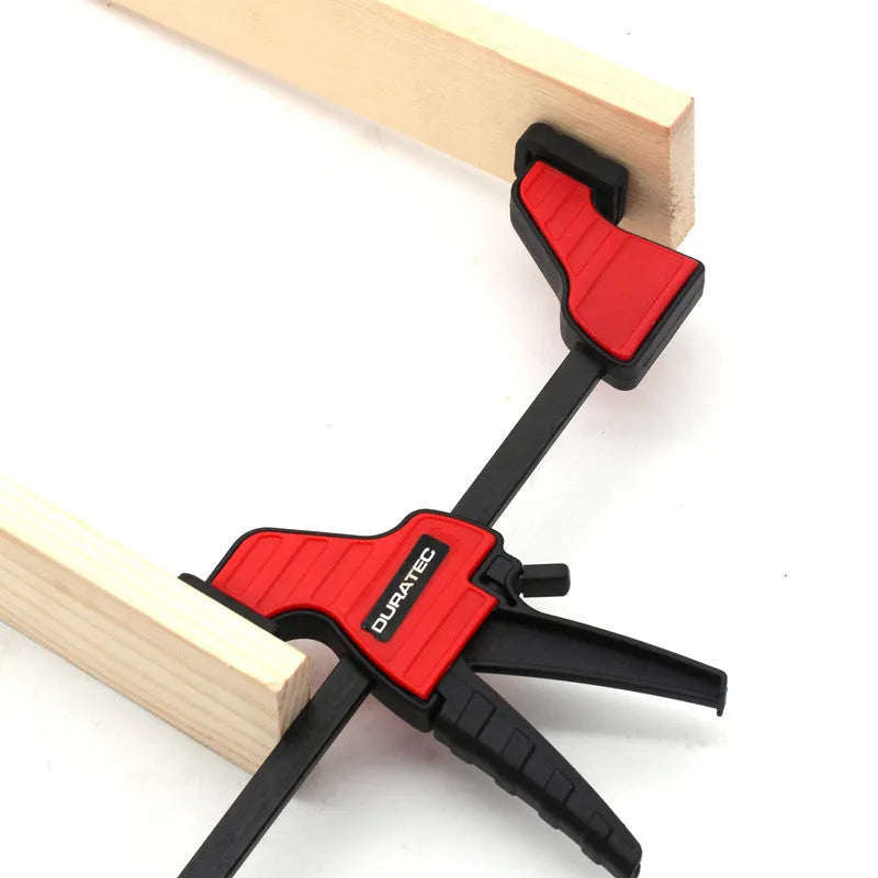 Black plastic one-handed ratcheting woodworking clamp with a quick-release trigger and soft rubber protective grips.