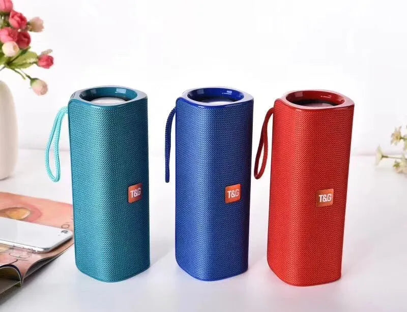 Cloth-covered portable Bluetooth speaker in multiple colours showing USB port and control buttons.
