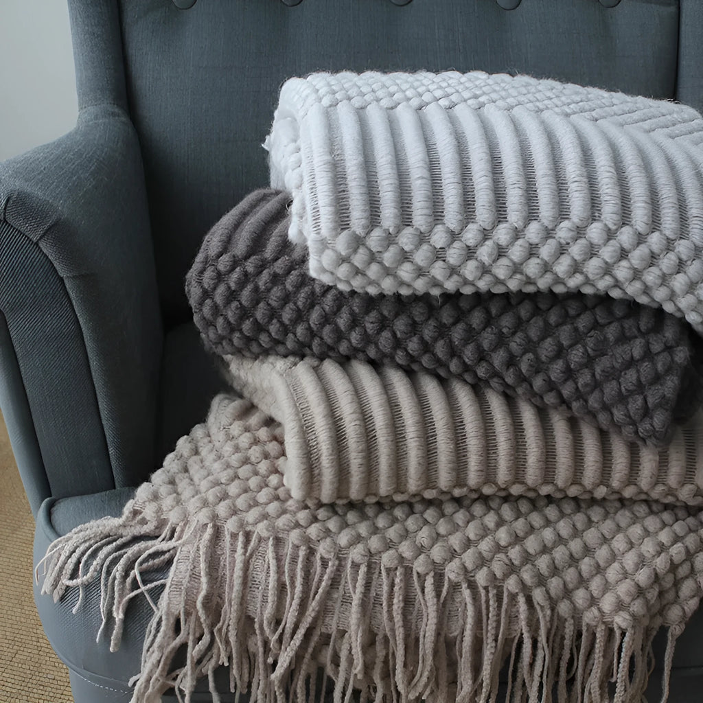 Small rectangular polyester nap blanket in neutral colour on a sofa, showing its 127 cm by 170 cm size.