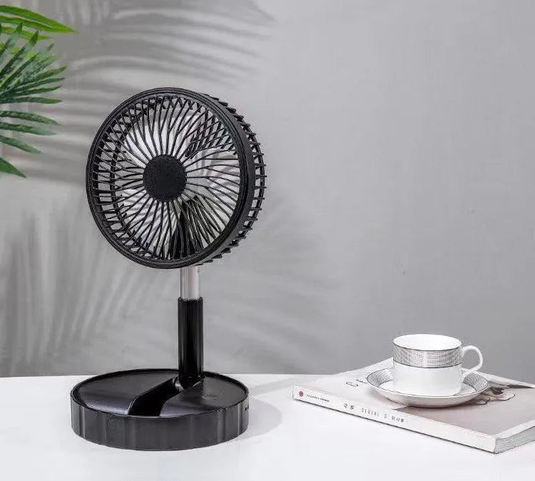 Black portable telescopic fan extended to full height on a table, showing its slim profile.