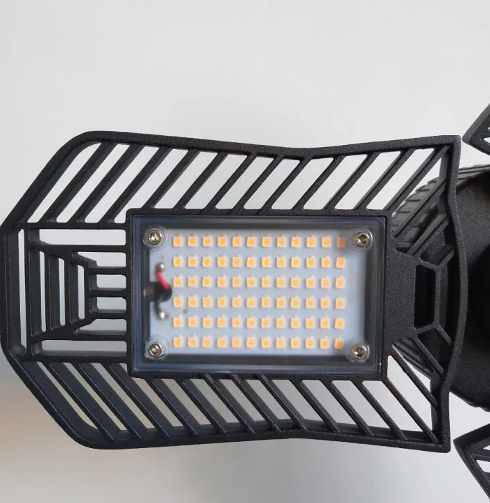 A foldable silver aluminium industrial LED garage lamp showing its waterproof housing and wide-angle light beam.