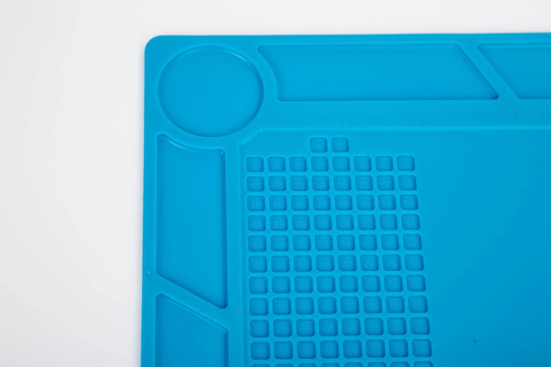 Blue silicone anti-skid watch repair mat on a workbench for horology tools.