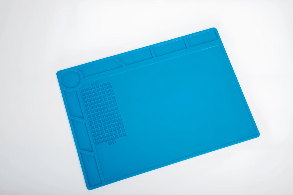 Blue silicone anti-skid watch repair mat on a workbench for horology tools.