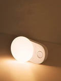 White Baseus rechargeable sensor night light with motion detection on a bedside table.
