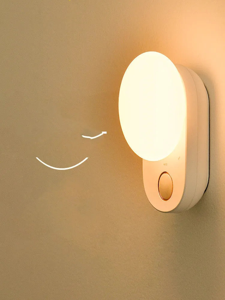 White Baseus rechargeable sensor night light with motion detection on a bedside table.