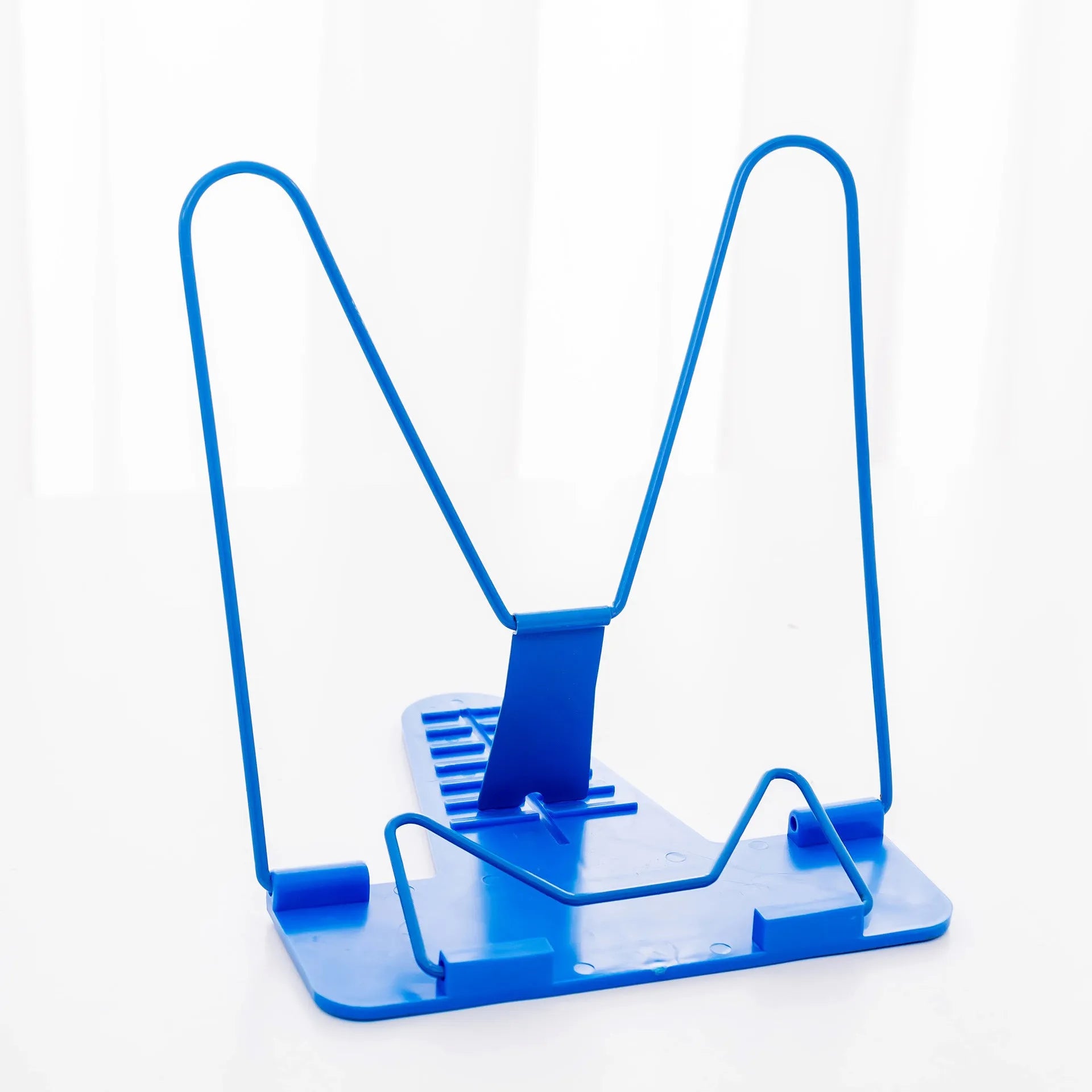 A red metal and plastic reading frame holding a book upright on a desk.