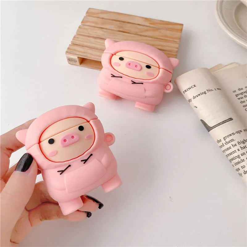 Pink silicone AirPods case cover with cartoon pig design, showing flip-style opening and hook attachment