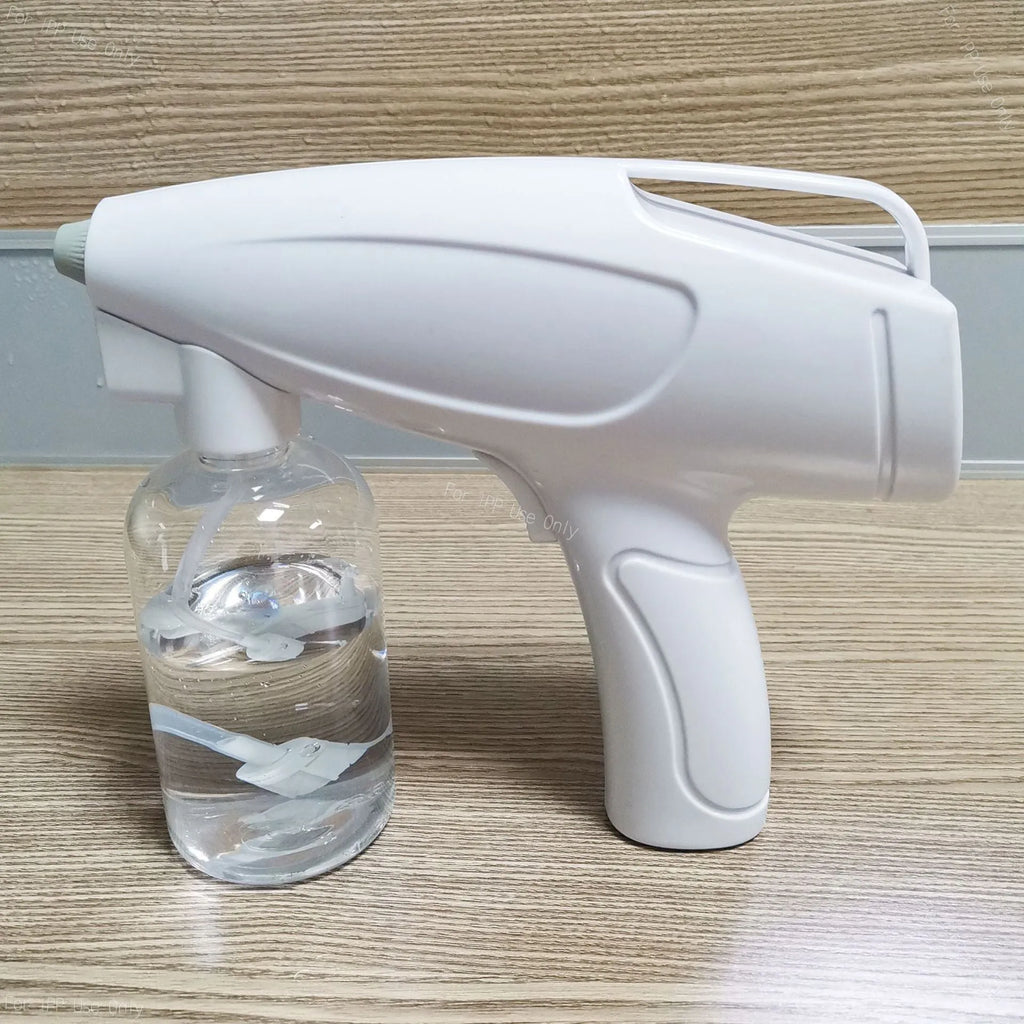 White handheld cordless electric disinfectant spray gun with bottle attached on a white background.