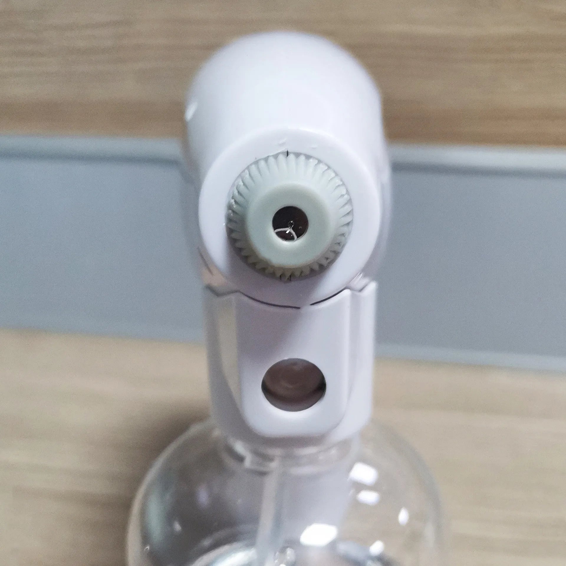 White handheld cordless electric disinfectant spray gun with bottle attached on a white background.