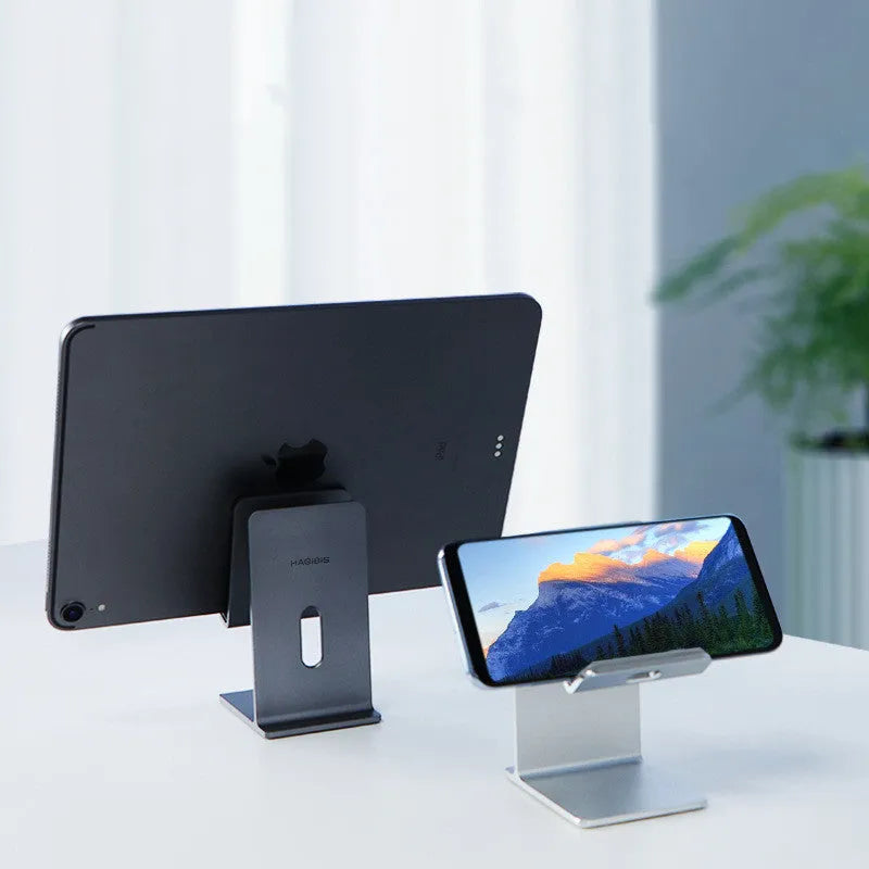 Alloy lazy bracket mobile phone holder in dark grey, clamped to a desk edge holding a smartphone.