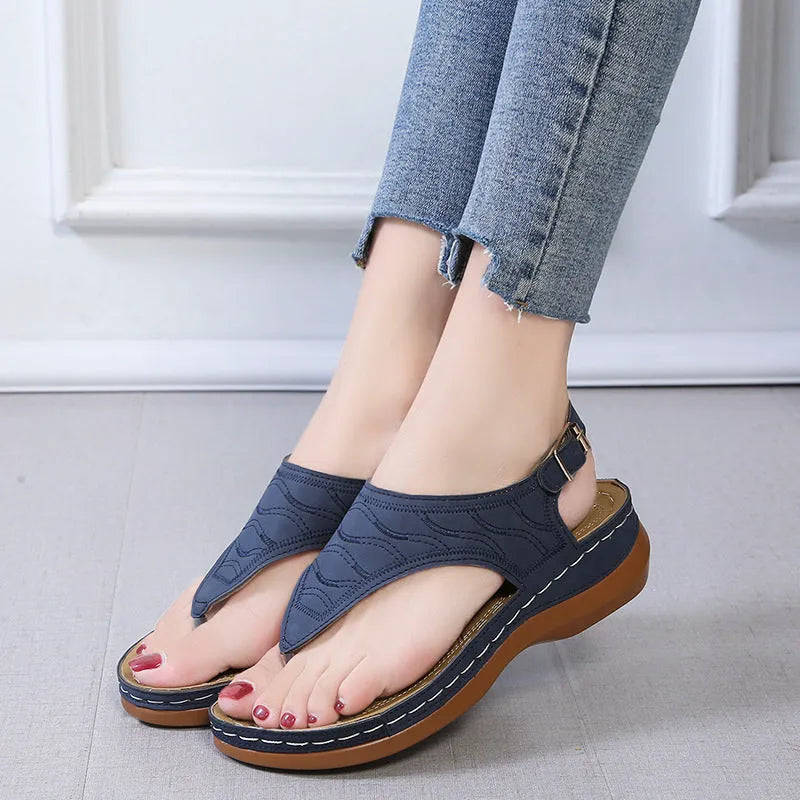 Women's black wedge heel sandals with an adjustable buckle back strap on a plain background.