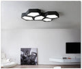 Geometric shaped black and white iron LED ceiling light with remote control on a table