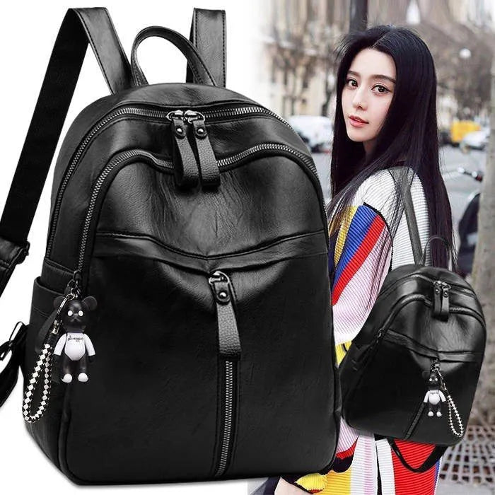 Black Pu leather soft surface backpack with double straps and a zippered opening.
