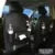 Black PU leather car seat back storage bag with multiple pockets hanging from a car headrest.