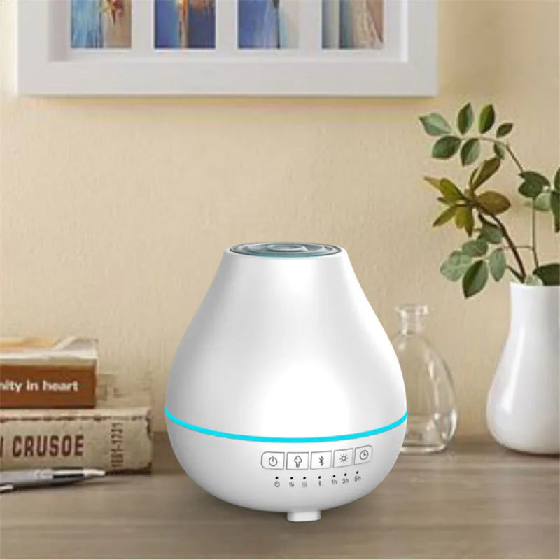 Round white Bluetooth humidifier and aroma diffuser with night light on a table.
