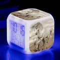 Small square cartoon-style LED alarm clock showing digital time on a plexiglass display.