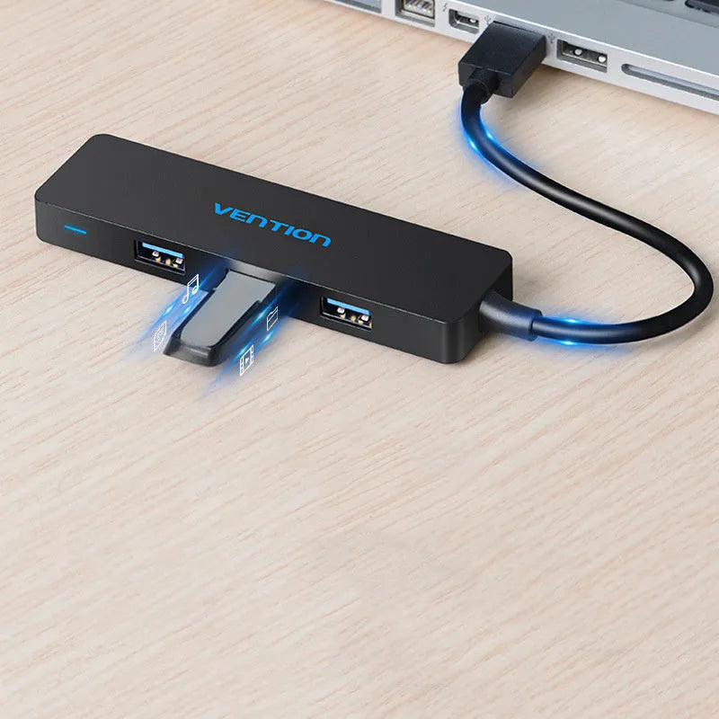 Black USB 3.0 hub with four ports and a short braided cable on a desk.