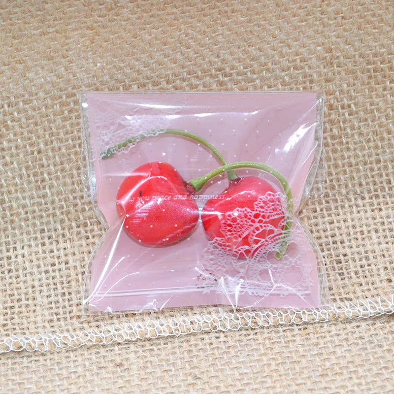 Clear pink self-adhesive plastic packaging bag with flap, shown next to a bar of soap.