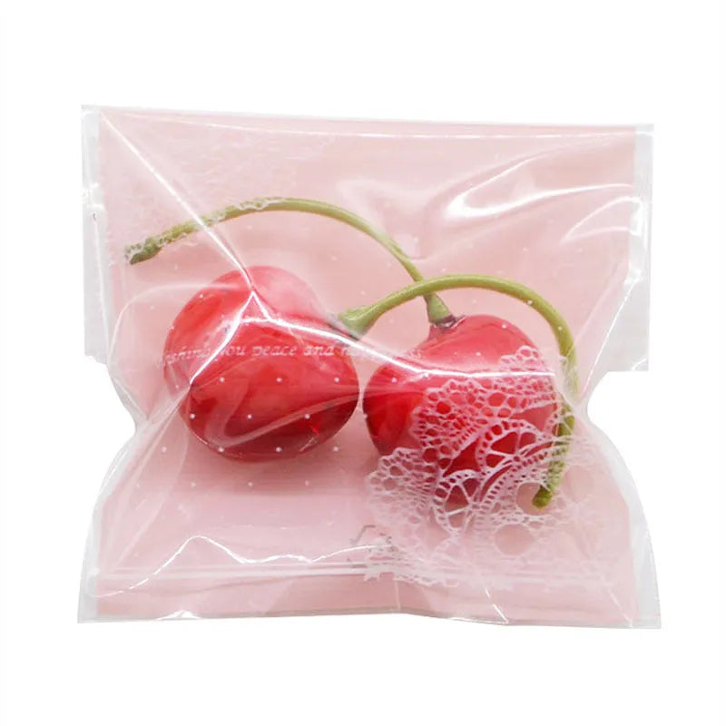 Clear pink self-adhesive plastic packaging bag with flap, shown next to a bar of soap.