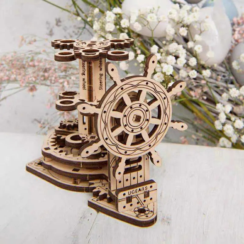 Natural wood rotating pen holder model kit with steering wheel mechanism on desk.