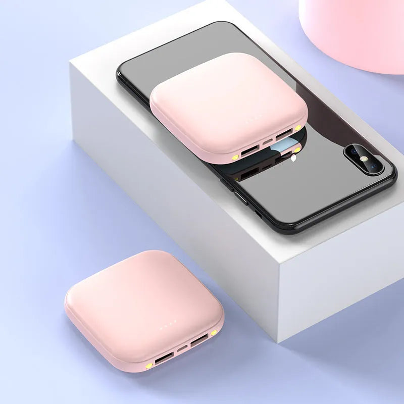 Compact black 20000mAh power bank with LED flashlight, showing scale next to a mobile phone.