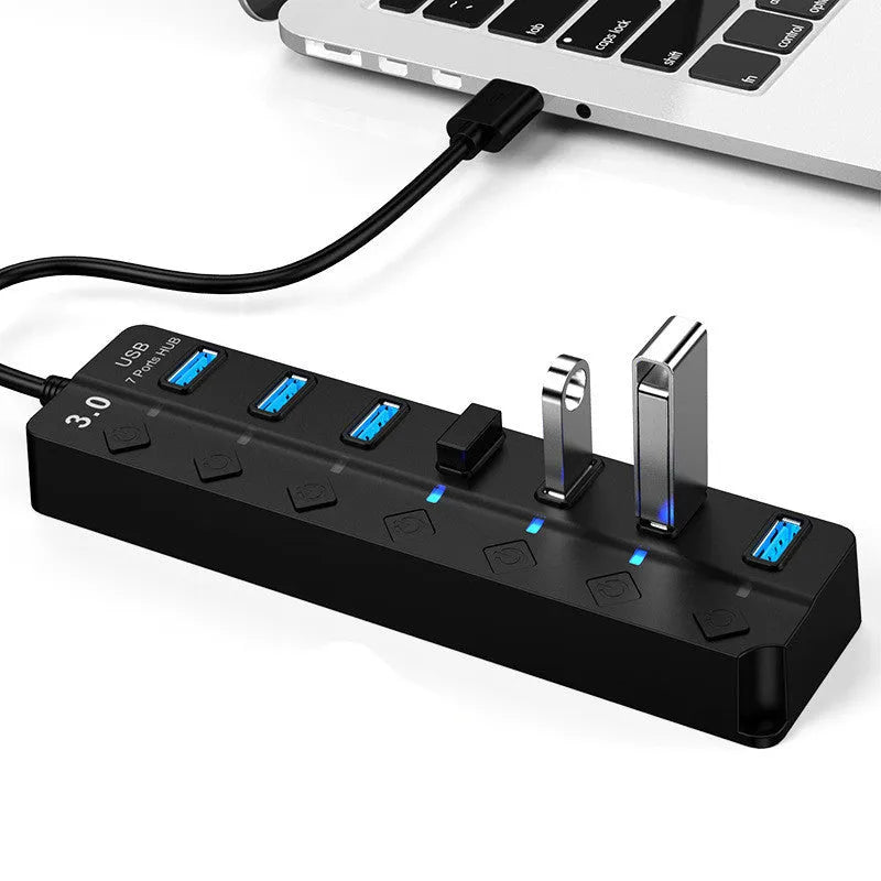Black 7-port USB 3.0 hub with external power supply on a desk.