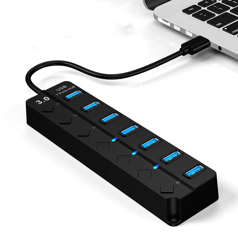 Black 7-port USB 3.0 hub with external power supply on a desk.