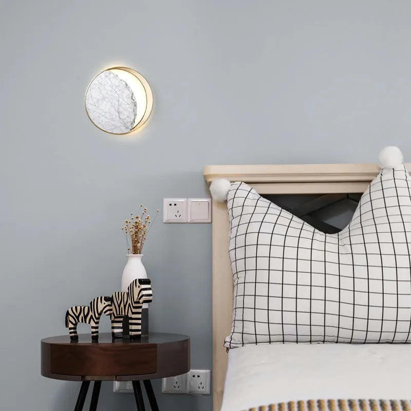 Circular marble and copper eclipse art design LED wall lamp mounted on a wall.