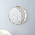 Circular marble and copper eclipse art design LED wall lamp mounted on a wall.
