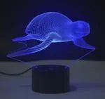 Small black and colourful 3D visual LED table lamp with remote control on a desk.