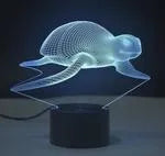 Small black and colourful 3D visual LED table lamp with remote control on a desk.