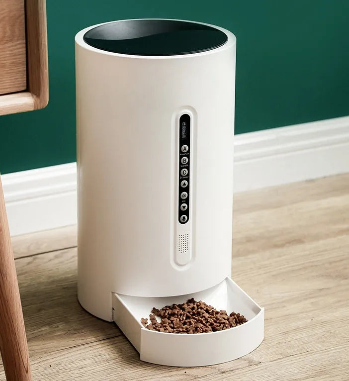 White smart pet feeder with digital timer and large food hopper on a counter.