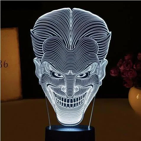 A 3D acrylic LED lamp with a square base, displaying one of its seven colour options on a desk.