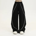 Black striped wide-leg pleated sports trousers showing loose fit and mid-waist design
