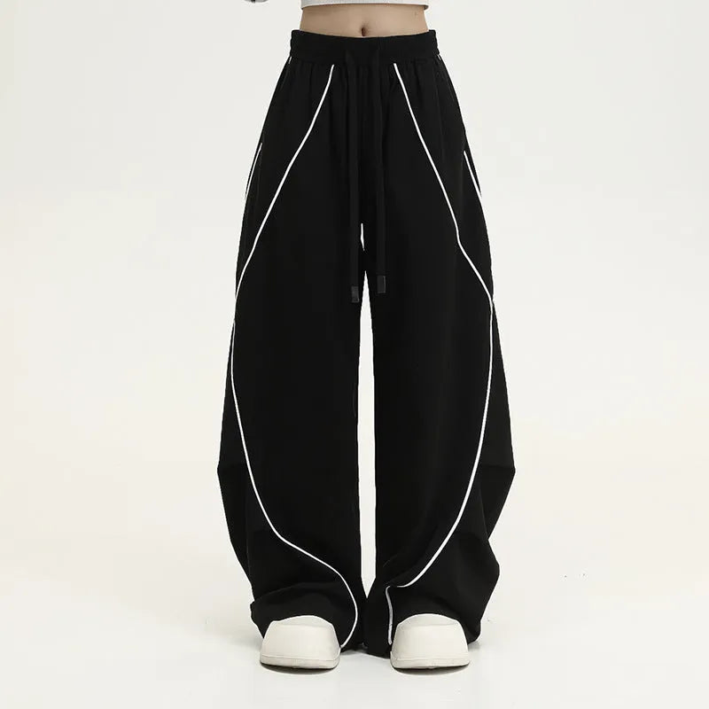 Black striped wide-leg pleated sports trousers showing loose fit and mid-waist design