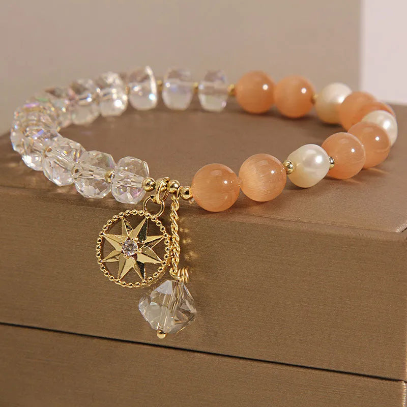 Women's gold-plated bracelet with an eight-pointed star design and a central inlaid orange opal crystal.