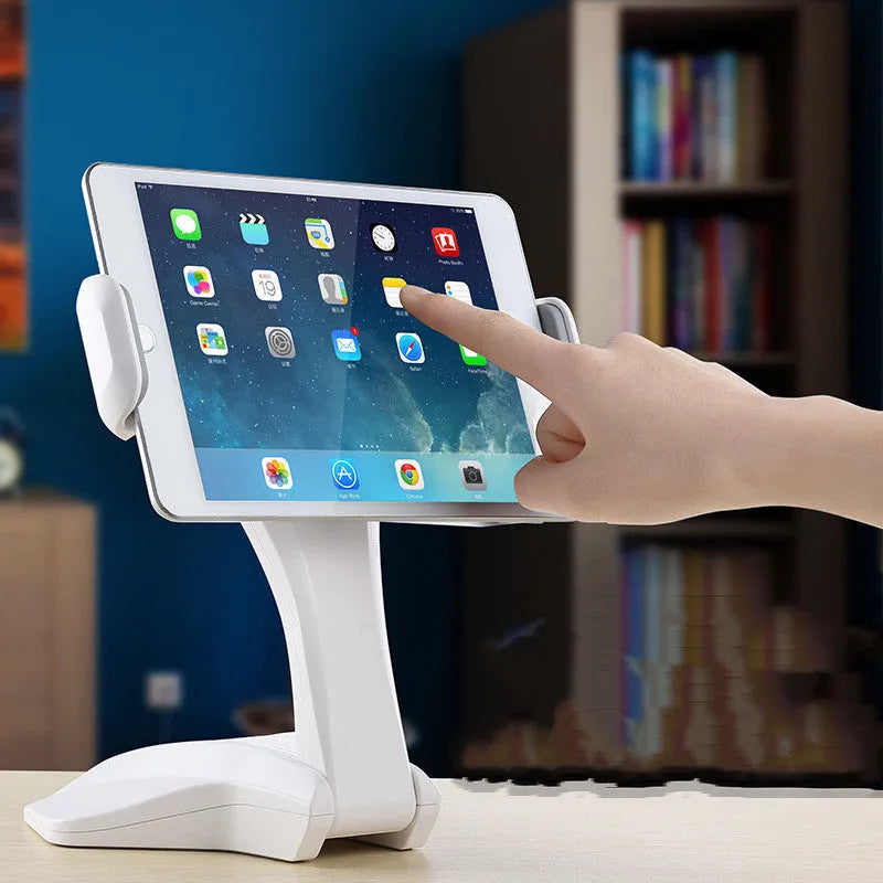 White adjustable tablet stand with a wide clip, holding a tablet on a table.
