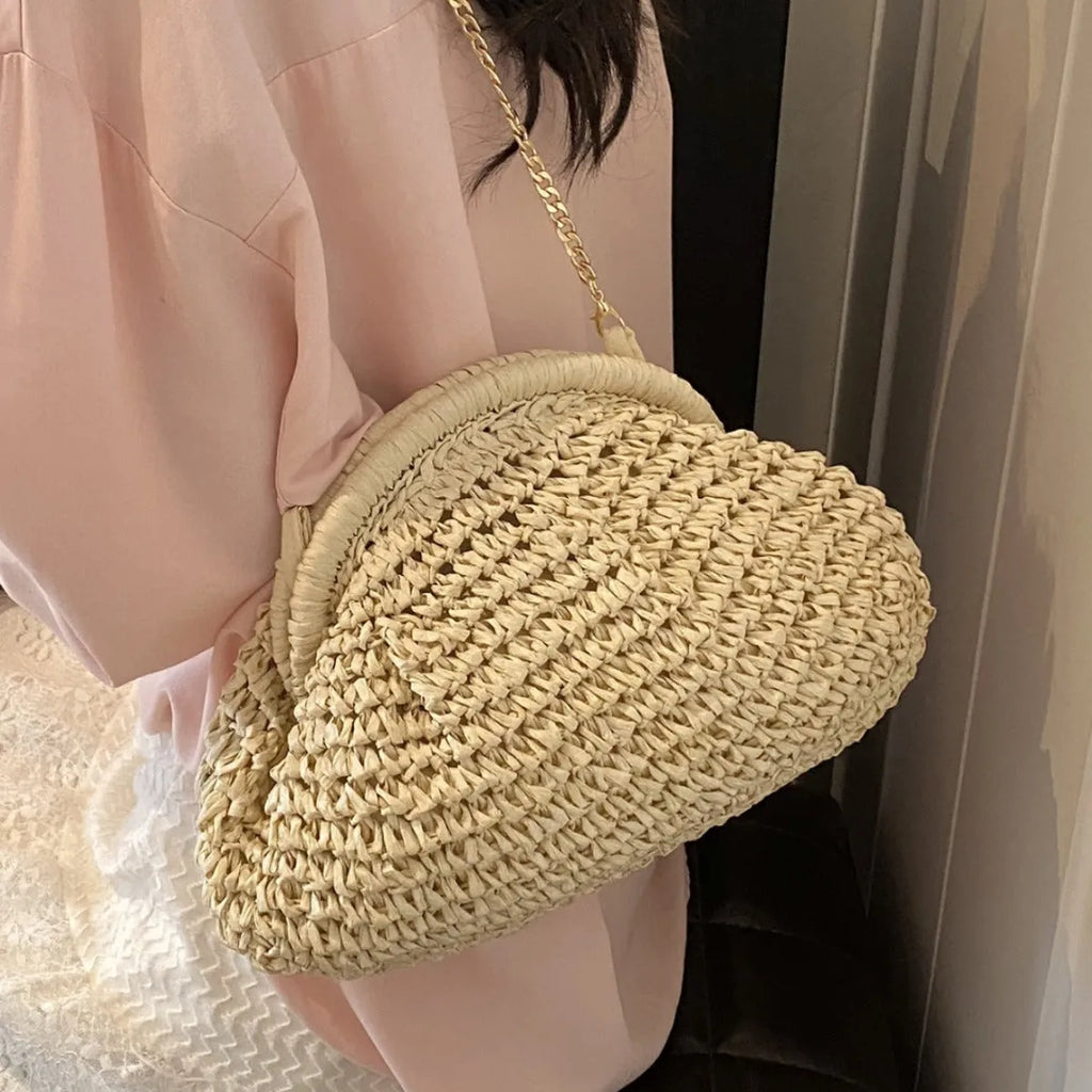 Women's beige shell-shaped paper straw bag with a metal chain strap.