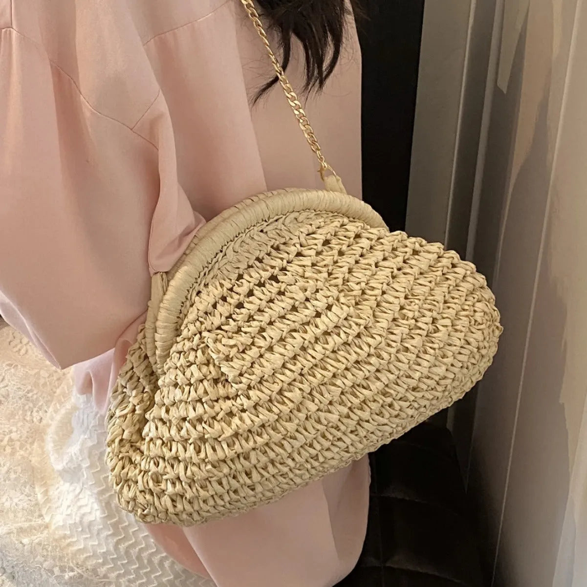 Women's beige shell-shaped paper straw bag with a metal chain strap.