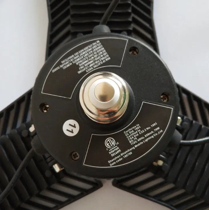 A foldable silver aluminium industrial LED garage lamp showing its waterproof housing and wide-angle light beam.