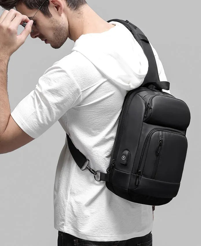 Black medium-sized PVC outdoor shoulder bag with an air cushion strap and internal organiser pockets.