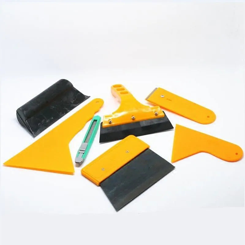 Seven-piece car foil tool set including scrapers, knives, tendon scraper, and pressing block on a table.