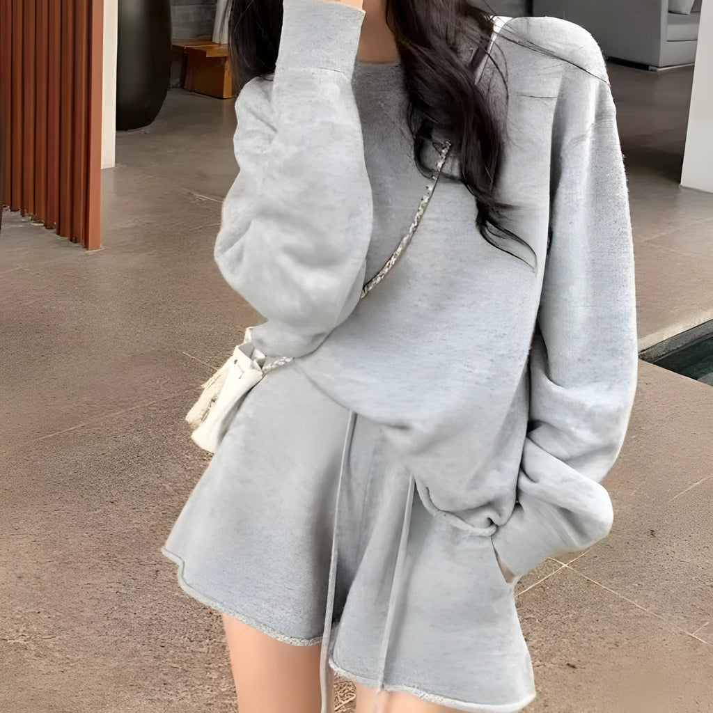 A woman's loose-fitting long sleeve knit sweater and matching wide-leg shorts set in a neutral colour.