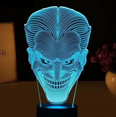 A 3D acrylic LED lamp with a square base, displaying one of its seven colour options on a desk.