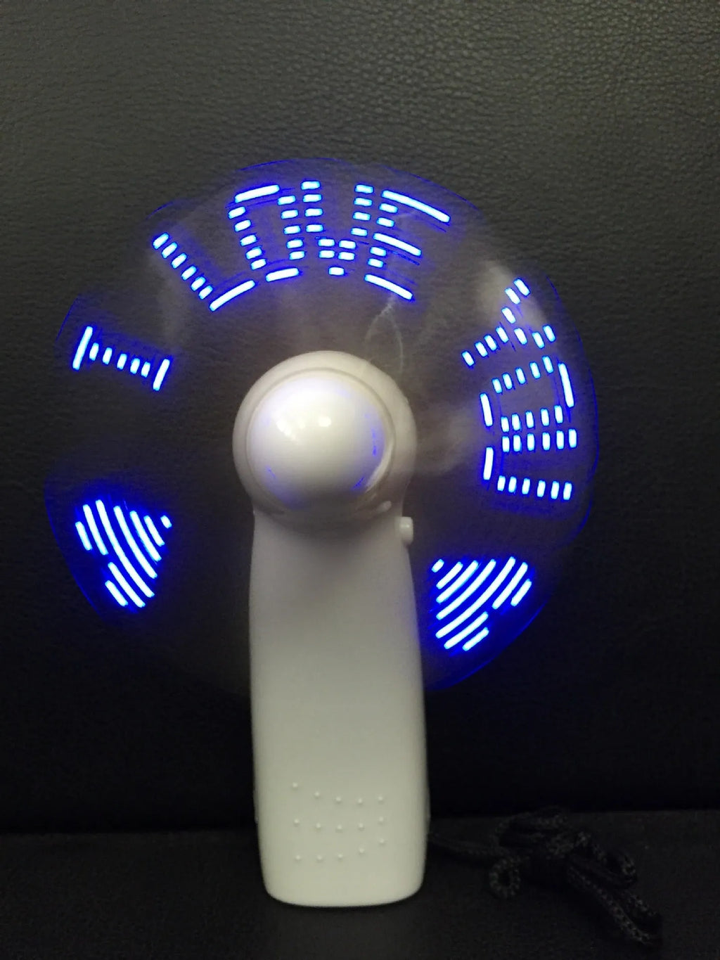 White handheld mini fan displaying a flashing blue and red 'I love you' LED pattern.