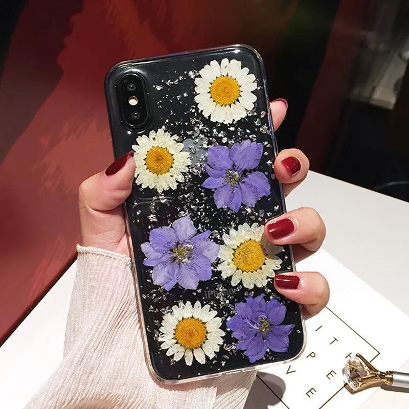 Clear TPU iPhone case with preserved pink dried flowers visible through transparent back cover