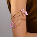 Close-up of a pink alloy armband with a hollow pattern design on a wrist.