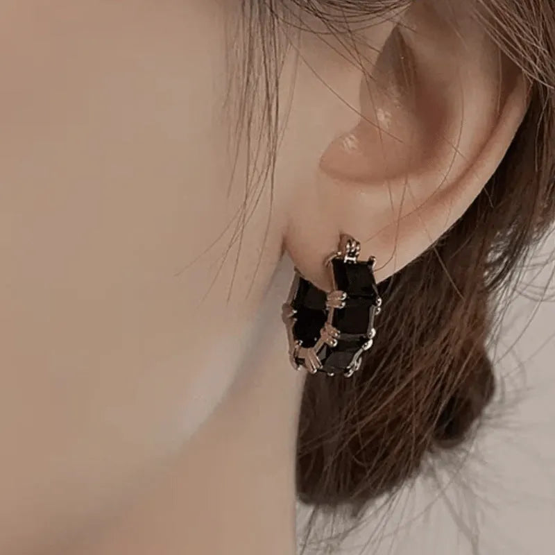 Geometric U-shaped gold earrings with a round black crystal zircon stone.